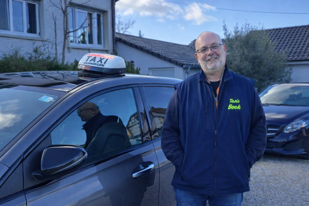 Chauffeur de Taxis Bock en gilet devant le véhicule à Mutzig